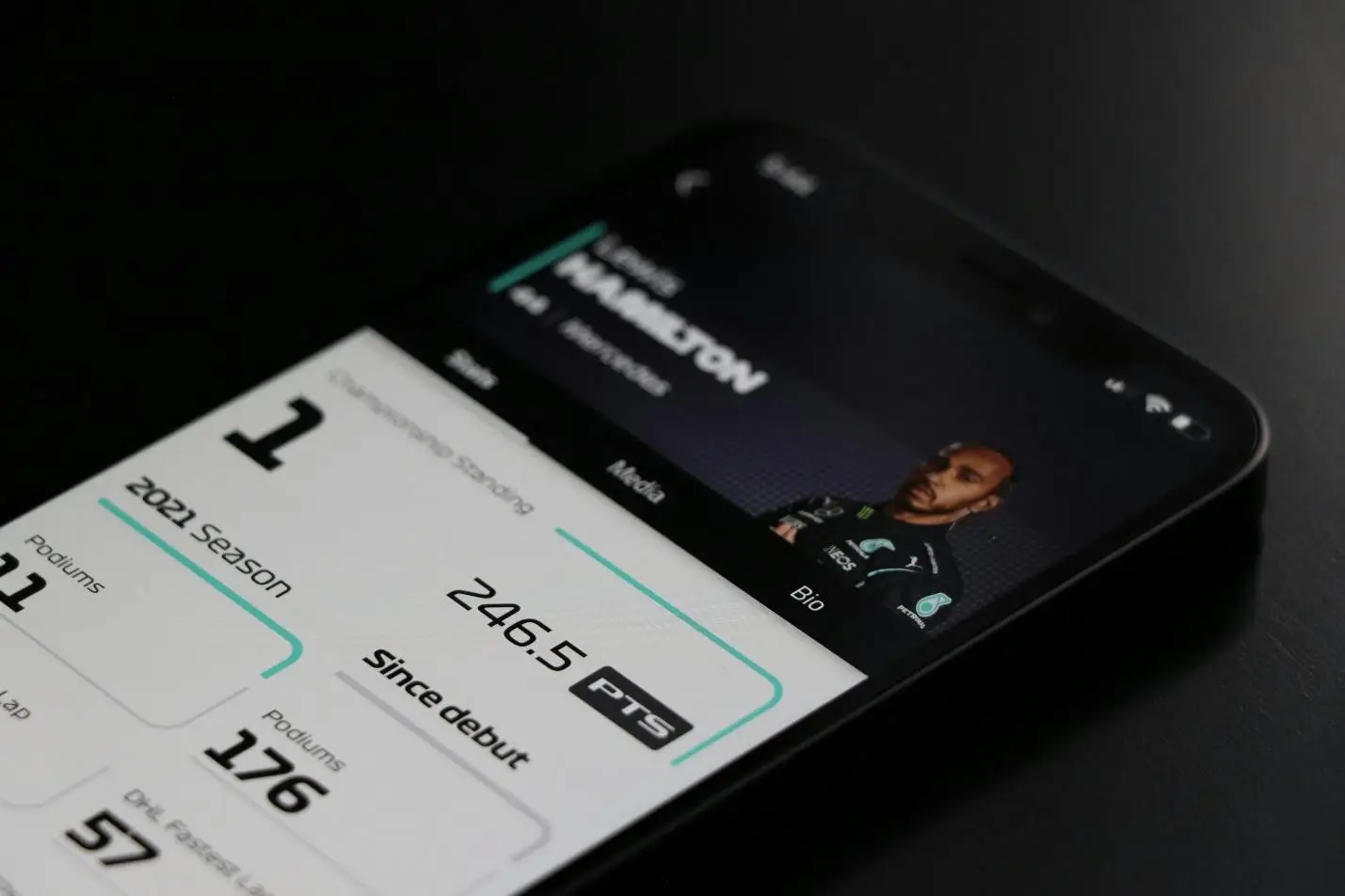 Smartphone displaying racing statistics and profile on dark surface in dim lighting