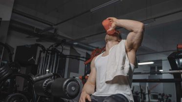 Strong man in gym drinking protein shake, emphasizing fitness and muscularity.